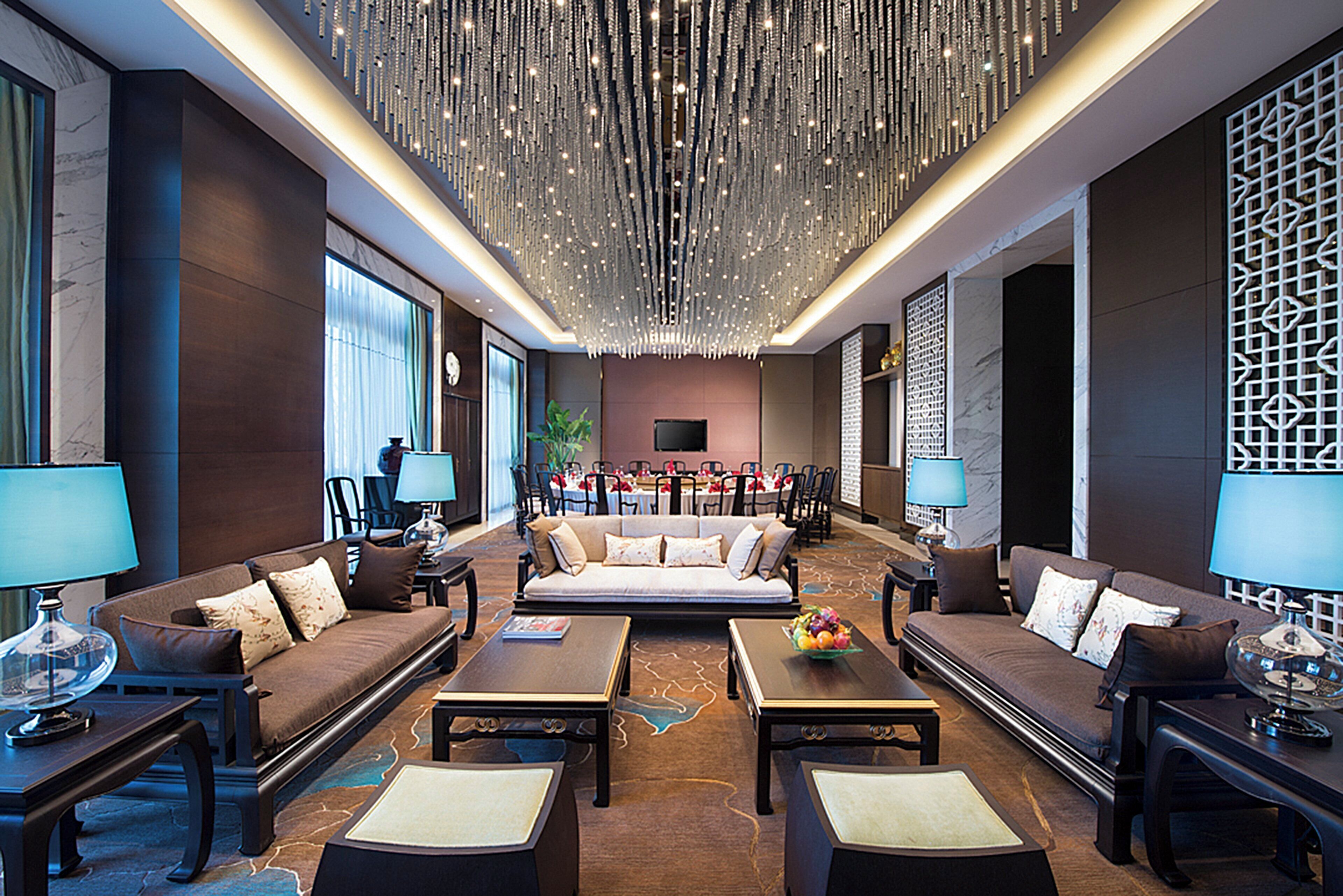 A spacious lobby with a high ceiling, a central seating area, and a dining setup.