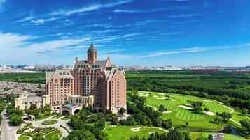 A large hotel with a prominent tower, surrounded by a well-maintained golf course and lush greenery.