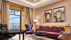 A hotel room with a large window, a round table, a purple armchair, a red sofa, and two wall-mounted mirrors. - Crowne Plaza Tianjin Jinnan by IHG (Tianjin)