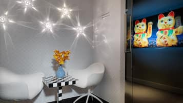 A modern room with a checkered table, a vase of flowers, and a wall-mounted TV displaying colorful cat figures.