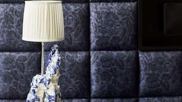 Een kamer met een donkere, patroonbezetting aan de wand, een witte lamp en een blauw-wit beeld op een reflecterend oppervlak.