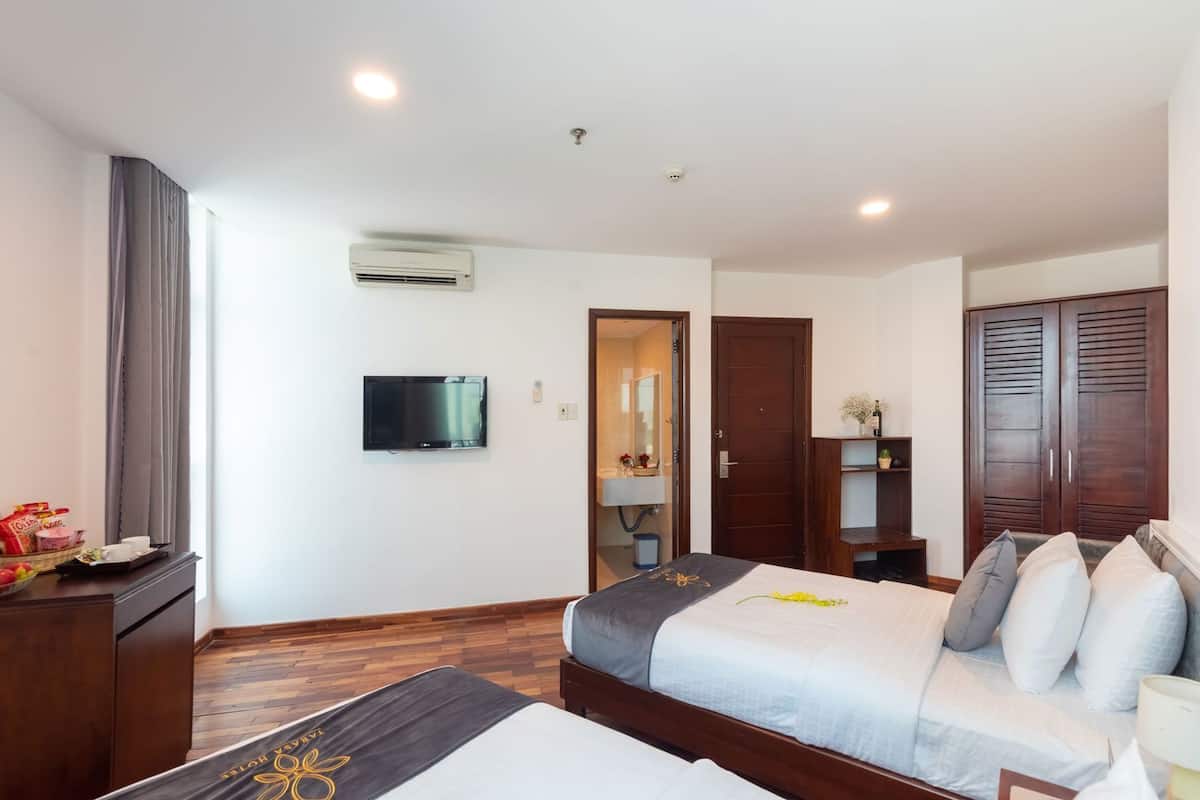 Una habitación de hotel con cama, televisión, armario y escritorio con lámpara.