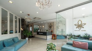 A modern hotel lobby with a reception desk, seating areas, and decorative plants. - Tarasa Hotel (Da Nang)
