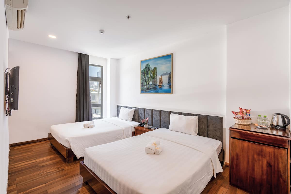 Habitación de hotel con dos camas, un cuadro en la pared, un aparador de madera y una ventana con cortinas.