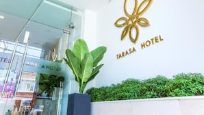 The exterior of Tarasa Hotel with a glass entrance, a large plant, and a gold logo on the wall. - Tarasa Hotel (Da Nang)