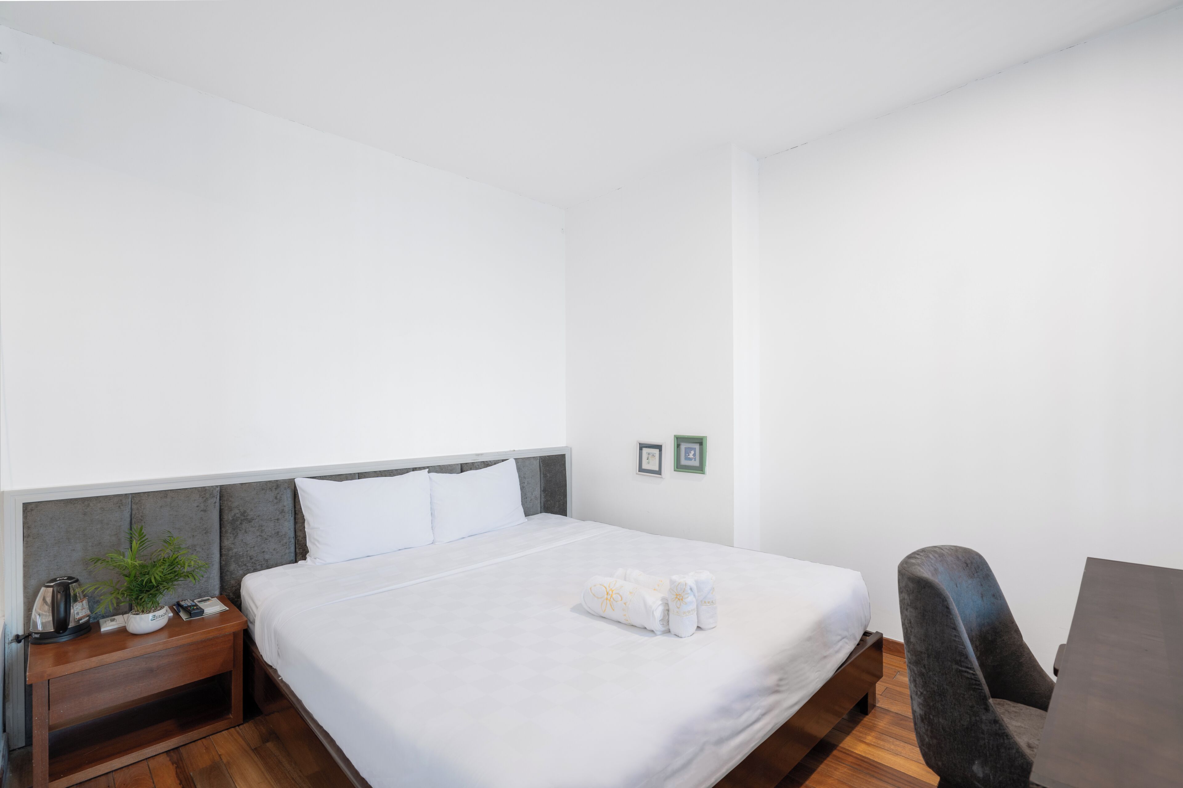 A hotel room with a bed, a nightstand, a chair, and a small table.