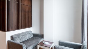 A modern living room with a grey sofa, a small wooden table, and a dark coffee table. - Tarasa Hotel (Da Nang)