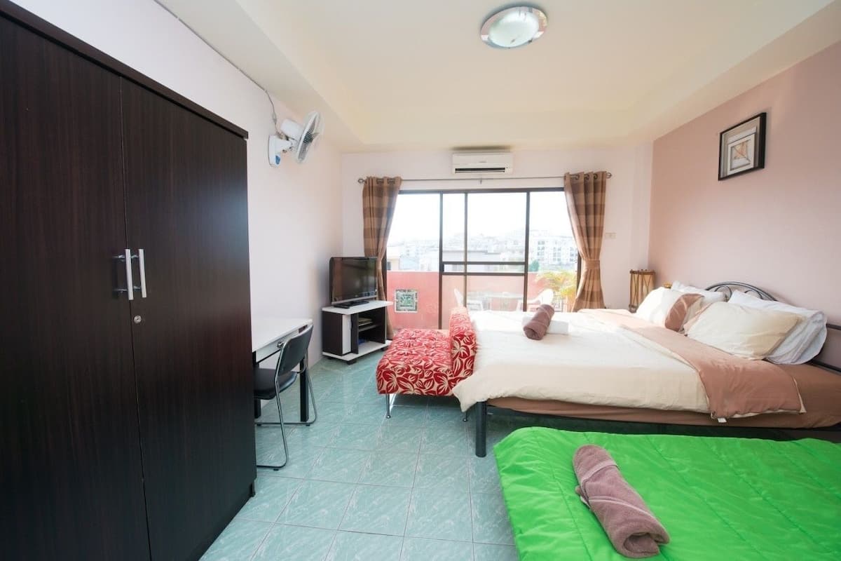 A hotel room with a bed, a desk, a wardrobe, and a window with curtains.