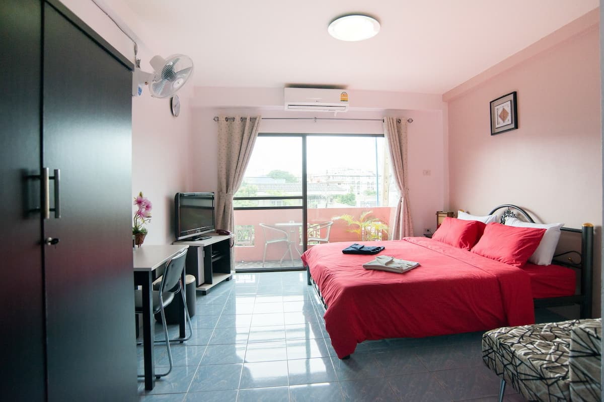 A hotel room with a bed, a desk, a chair, a TV, and a balcony with a view.