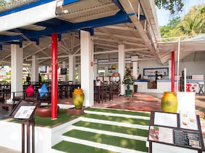 An outdoor seating area with tables and chairs, a reception desk, and a Christmas tree. - Kerala Coco Resort (Rayong)