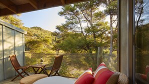 Ein Balkon mit Korbmöbeln, einem Tisch und einer Weinflasche.