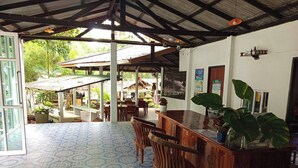 A covered outdoor dining area with a patterned floor, wooden furniture, and a bar counter. - Faye Orchid Resort (Ko Chang)