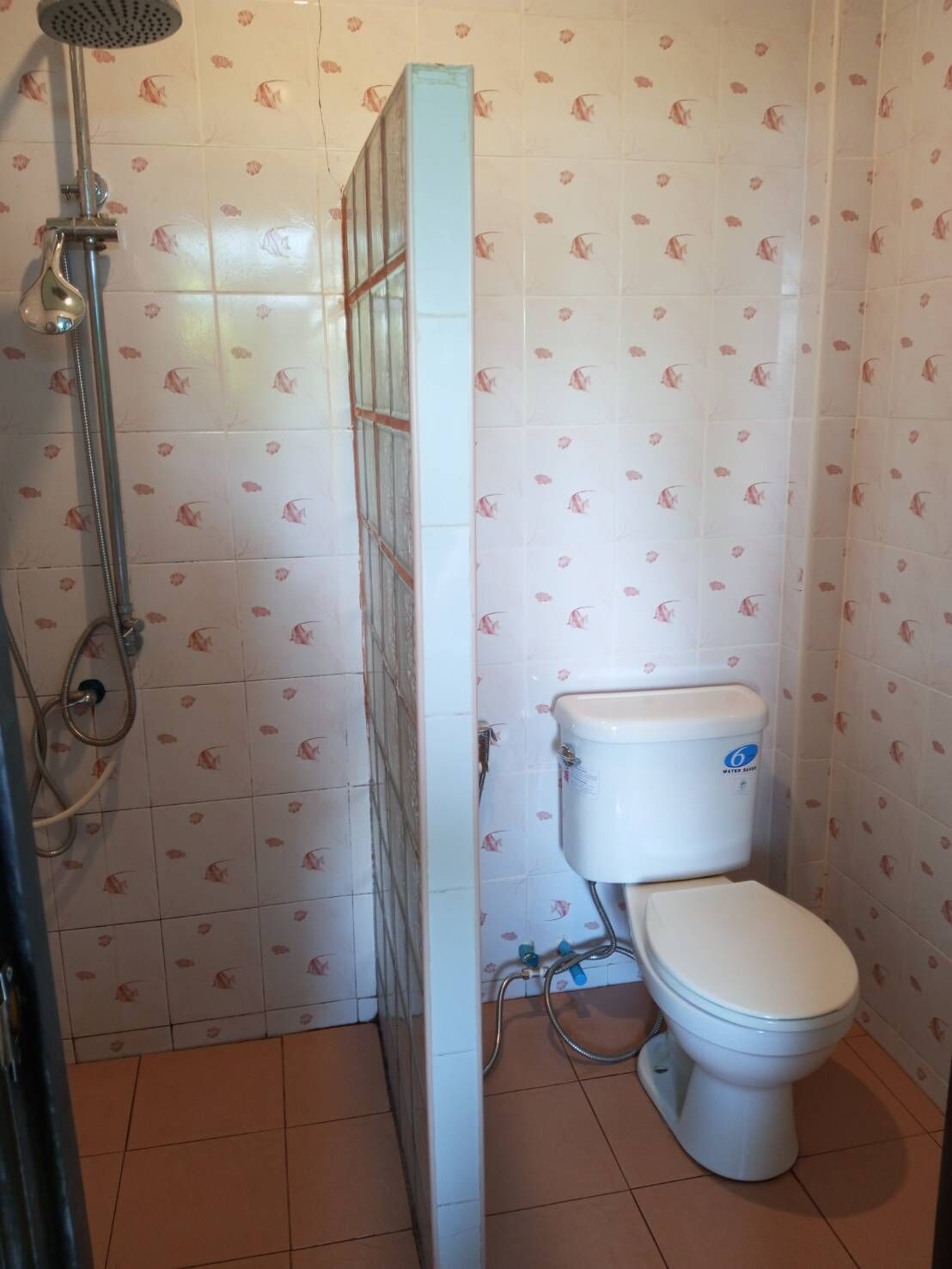A bathroom with a toilet, shower, and tiled walls.