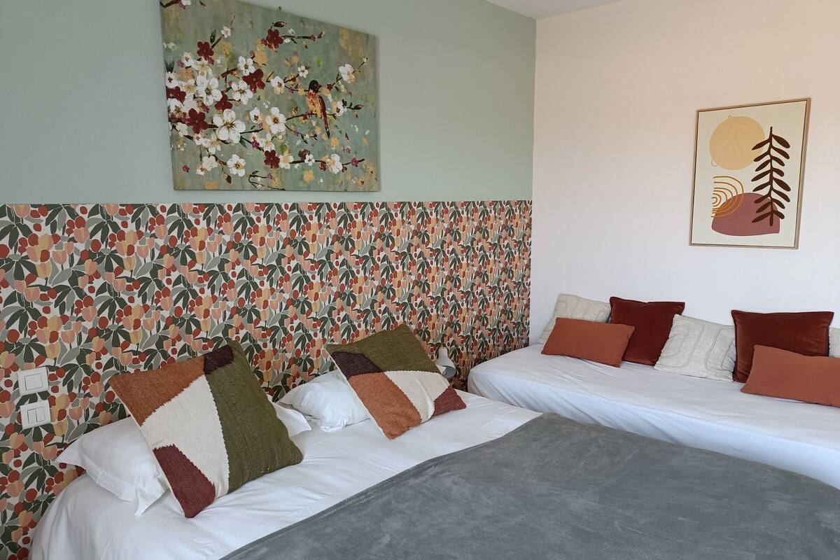A bedroom with two beds, a floral-patterned headboard, and artwork on the walls.