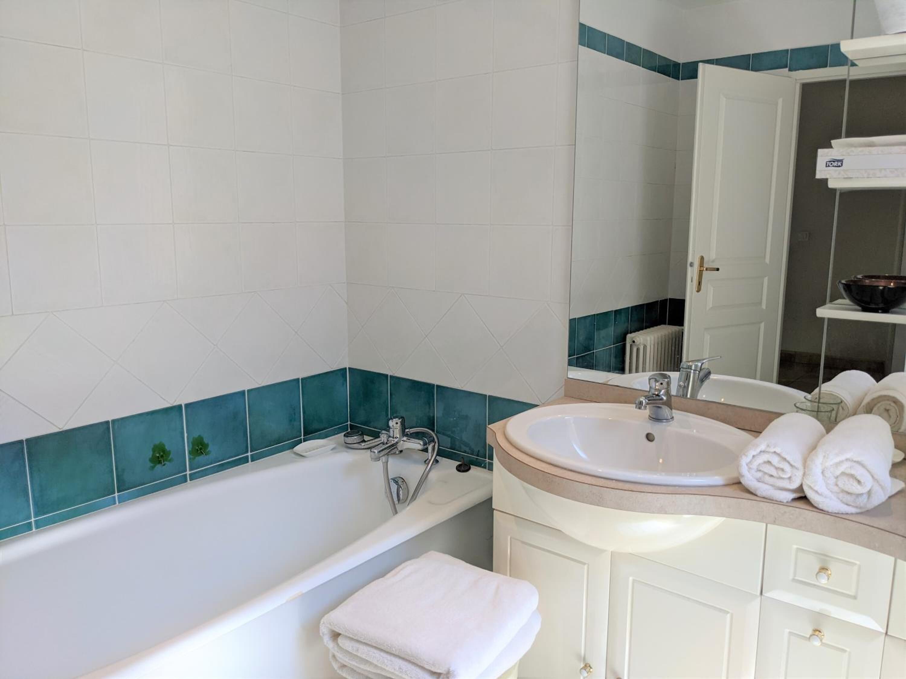A bathroom with a bathtub, a sink, and a mirror.