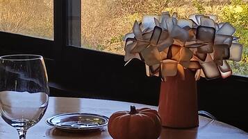 A table with a vase of flowers, a pumpkin, and a wine glass.