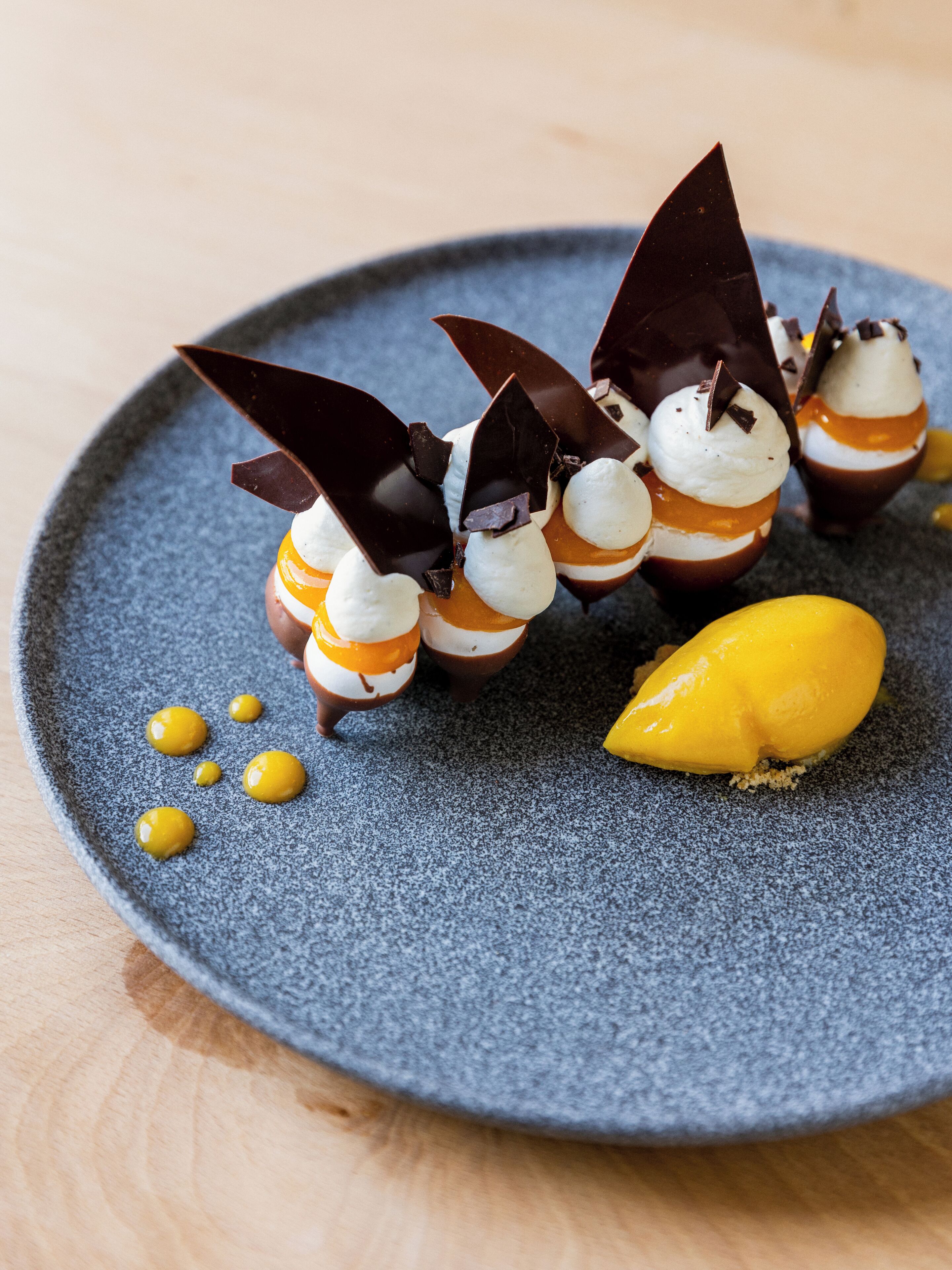 A dessert plate with chocolate-covered treats and a mango slice.