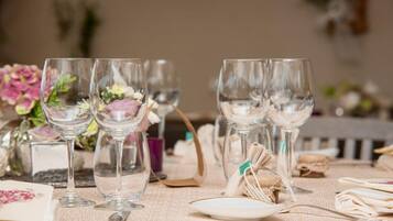 A table set with wine glasses, a plate, and a spoon, with a floral arrangement in the background.