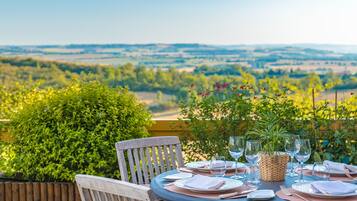 A table set for dining with a view of a countryside landscape.