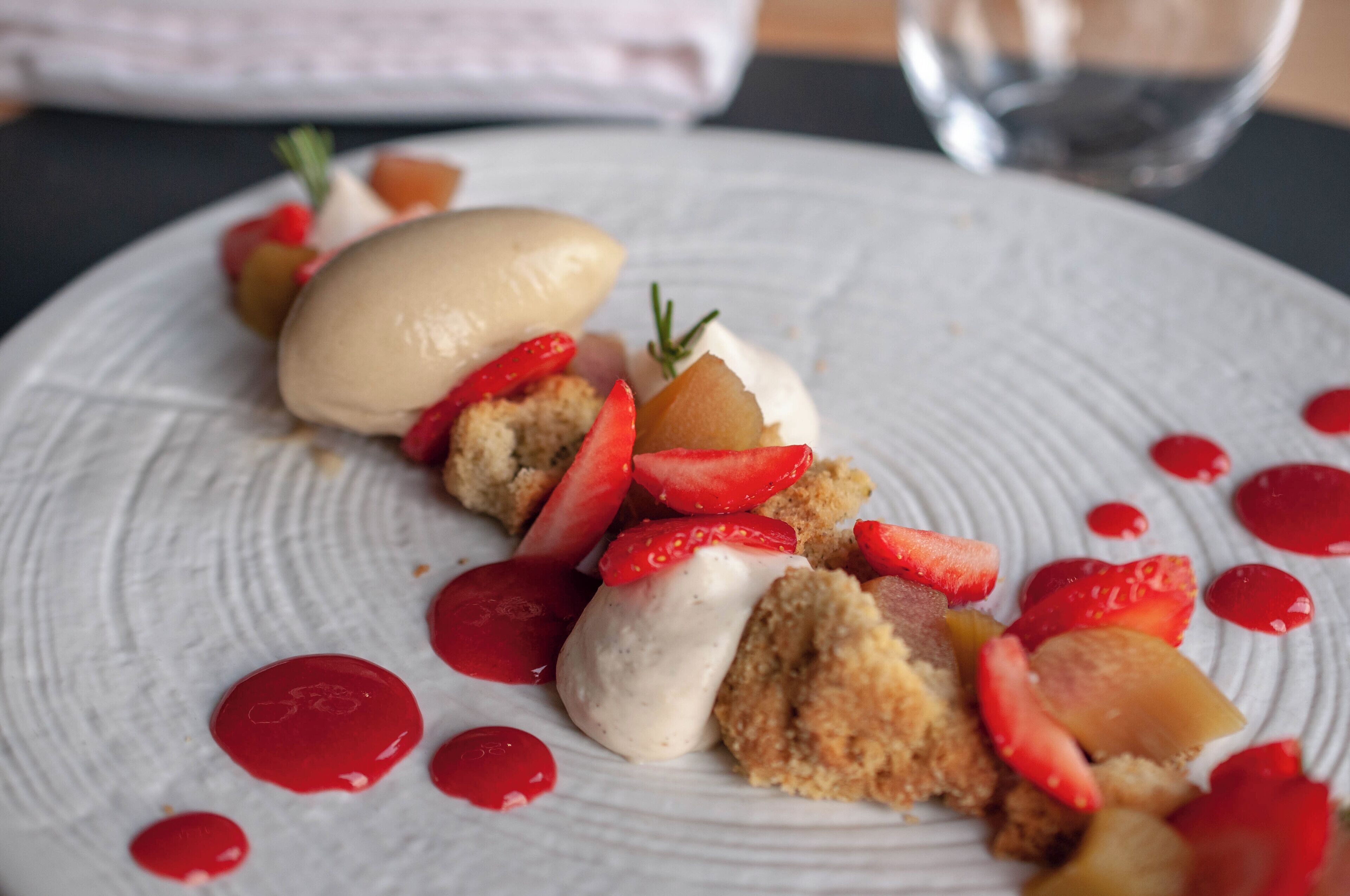 A dessert plate with a scoop of ice cream, strawberries, and a piece of cake.