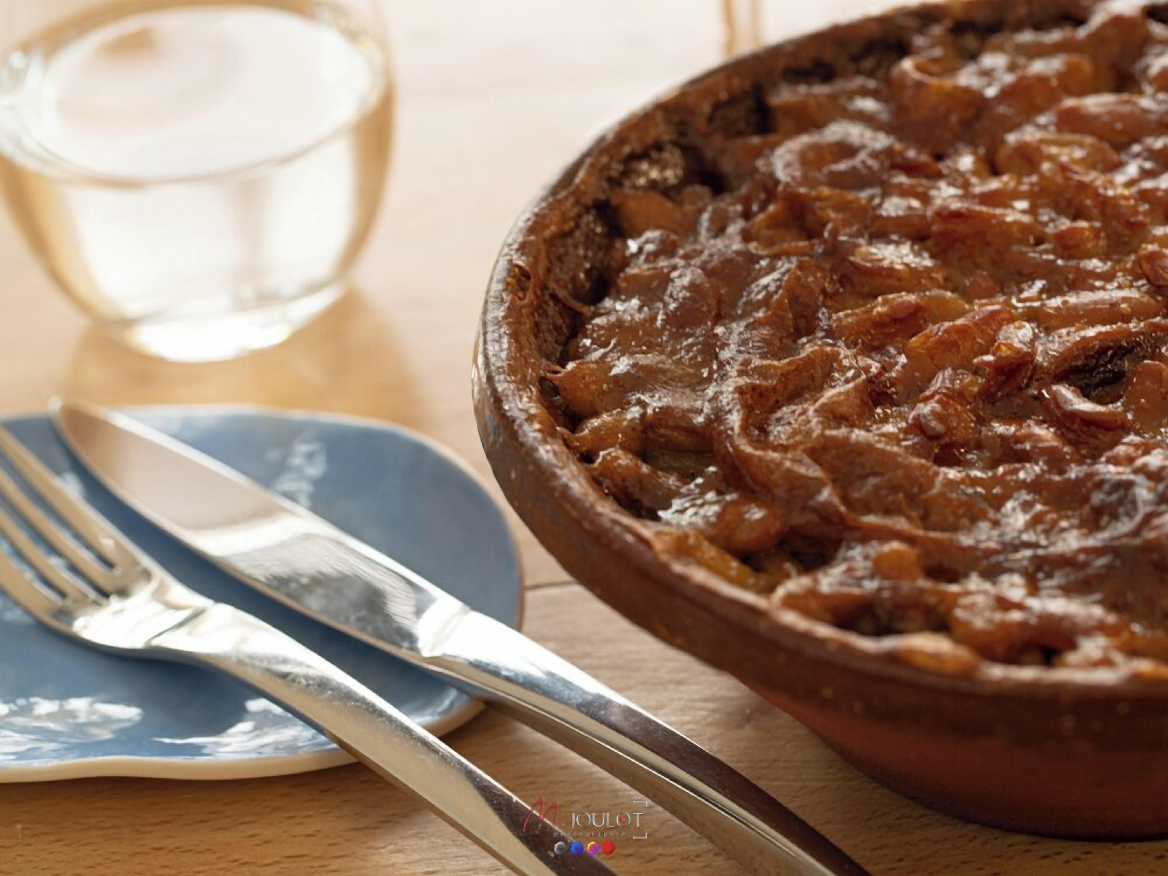 A bowl of stew with a fork and knife on a plate beside it.