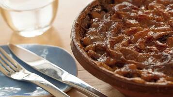 A bowl of stew with a fork and knife on a plate beside it.