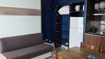 Un espacio habitable compacto con sofá, mesa de comedor y zona de cocina.