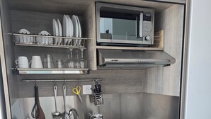 Cocina compacta con microondas, lavamanos y espacio para utensilios.