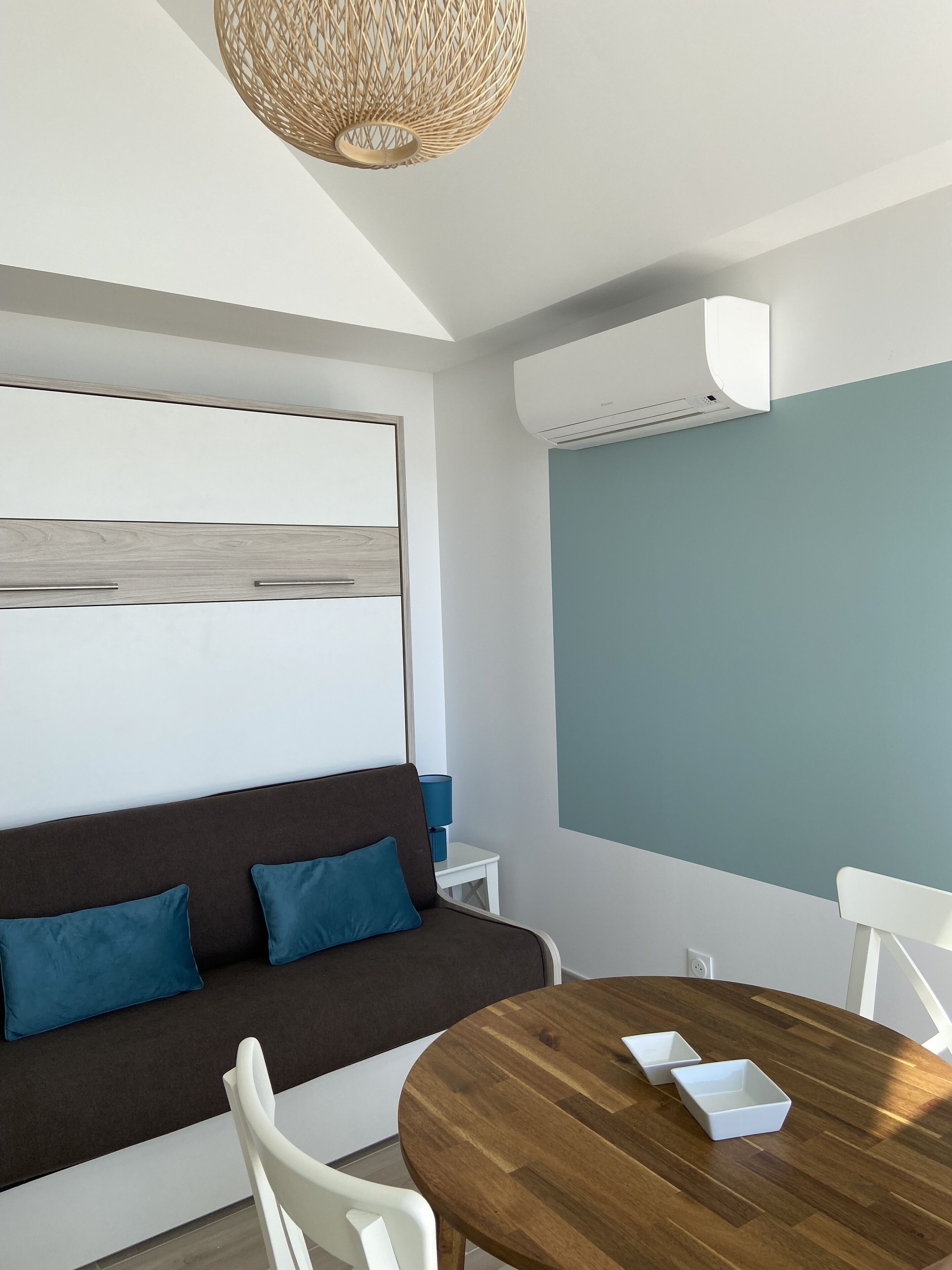 A modern room with a brown sofa, white chairs, a wooden table, and a blue accent wall.