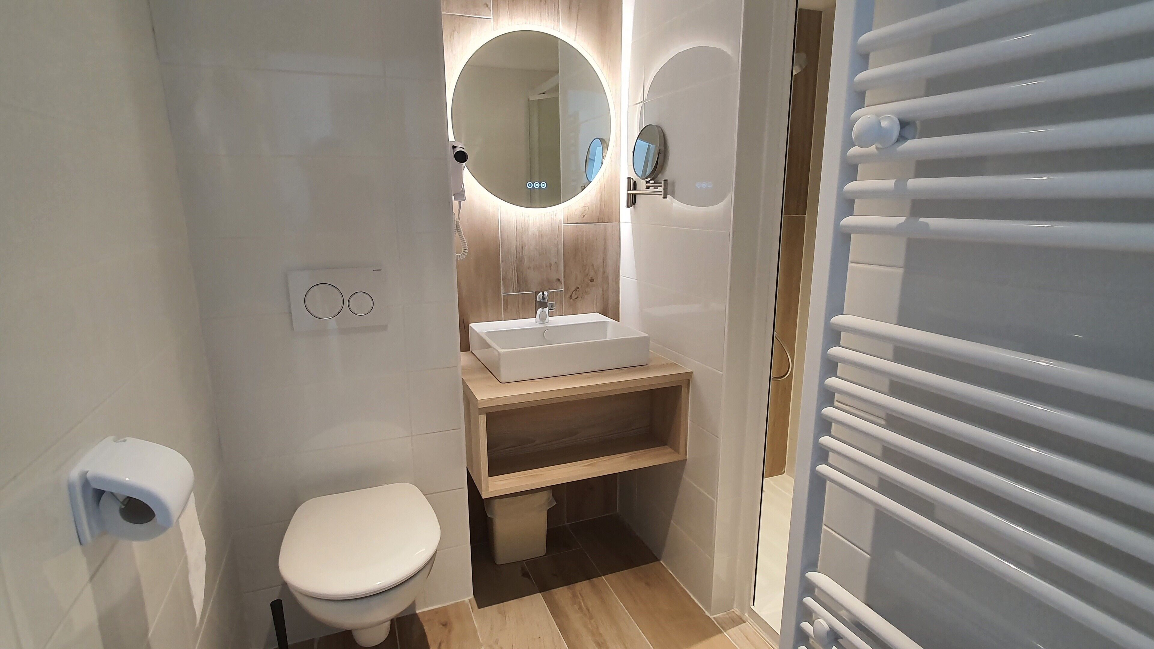 Une petite salle de bain comprenant des toilettes, un lavabo, un miroir et un porte-serviettes.