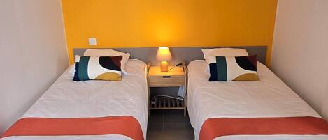 A hotel room with two beds, a nightstand with a lamp, and a picture on the wall.