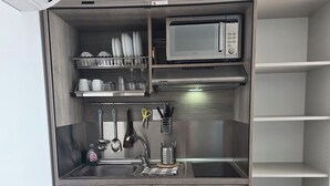 Una cocina compacta con microondas, lavabo y armarios de almacenamiento.