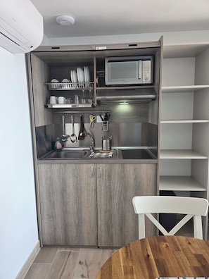 A compact kitchen with a microwave, sink, and storage cabinets. - La Vigie Vacances (Les Sables-d'Olonne)