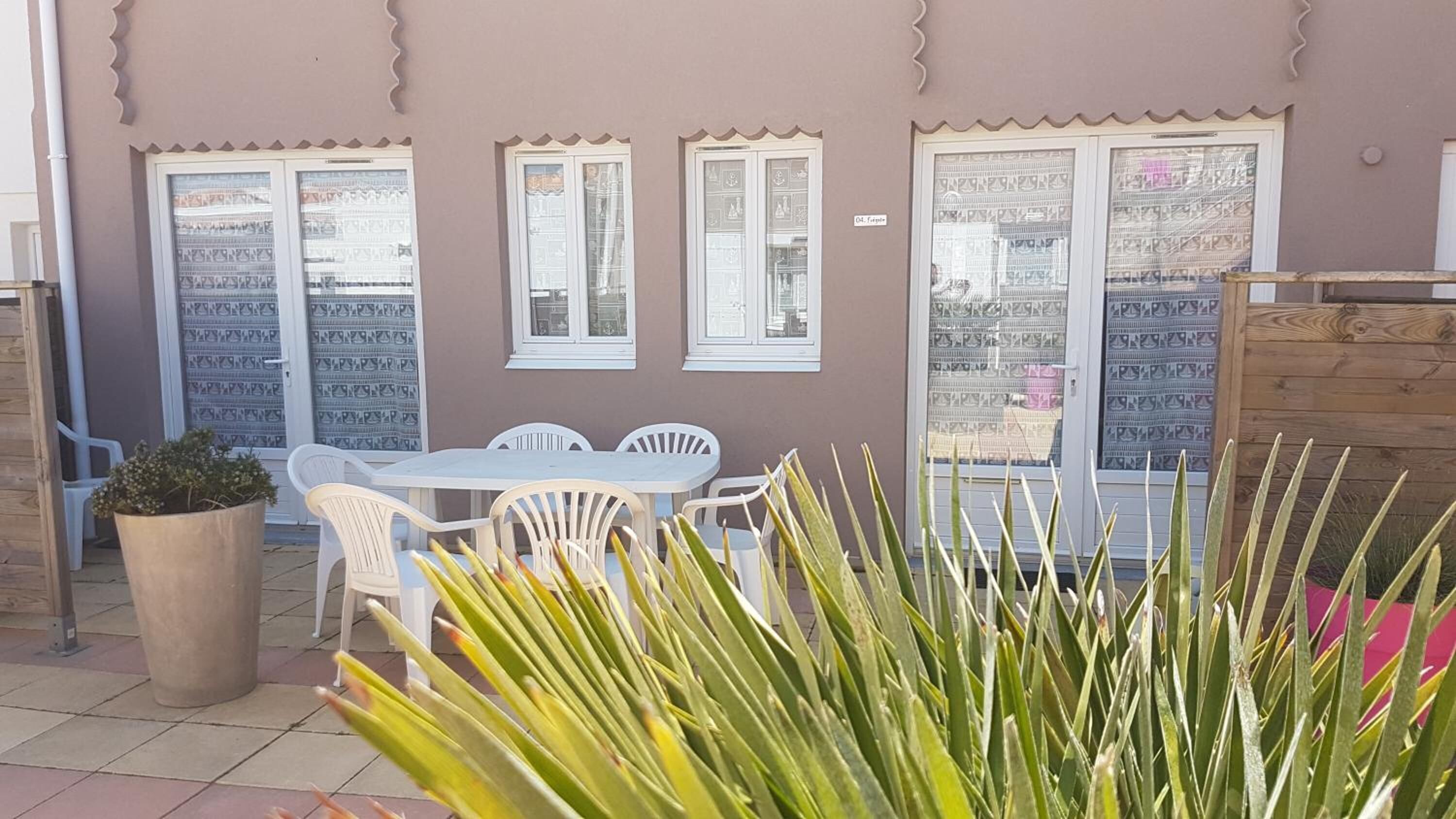Un patio con una mesa, sillas, una planta en maceta y un mueble de madera.