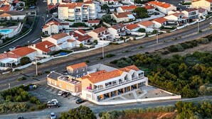 Vista aérea de una propiedad costera con un edificio amplio que cuenta con un patio espacioso y vistas al mar.
