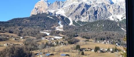Un paysage de montagne avec un ciel dégagé, mettant en valeur un sommet imposant et une vallée parsemée de bâtiments.