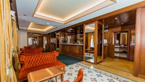 Un hall de hotel con una zona de estar que incluye sofás tapizados en naranja y una mesa de madera.