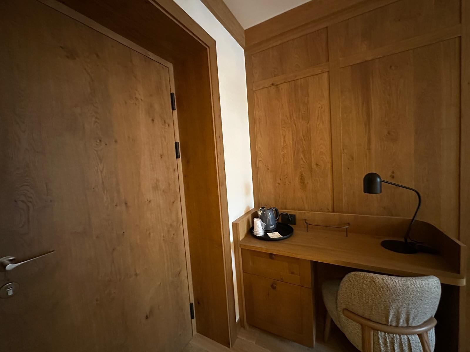 Una stanza in legno con una scrivania, una sedia e una porta.