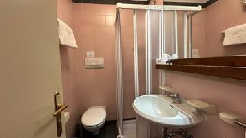 Ein Badezimmer mit Dusche, Toilette, Waschbecken und Handtuchhalter.