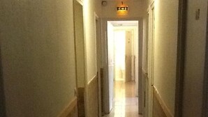 Un pasillo largo y estrecho con piso de baldosas brillantes y paneles de madera en las paredes.