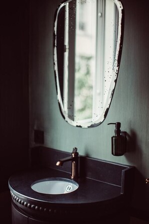 Un baño con un lavabo redondo, un grifo y un dispensador de jabón.
