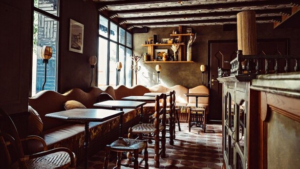 Interior acogedor de restaurante con mobiliario de madera, suelo de ladrillo y techo rústico.
