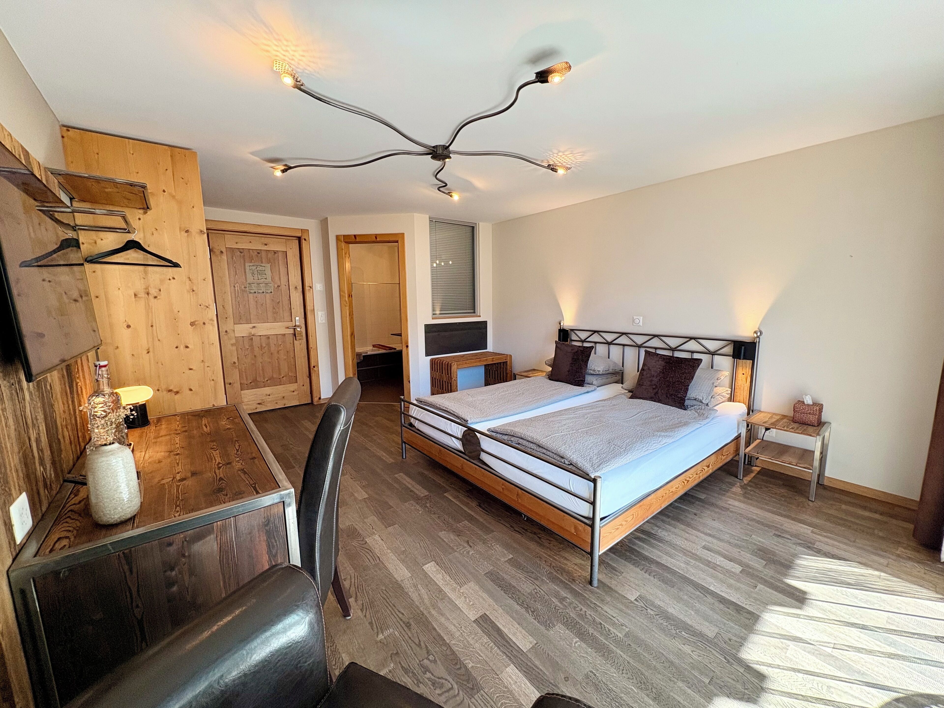 A bedroom with a bed, bedside tables, a desk, and a chair.