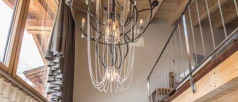 Un salon moderne avec un plafond en bois, un lustre, un canapé et une lampe sur pied.