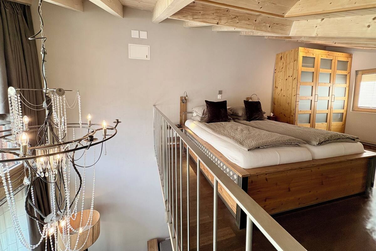 Une chambre à coucher avec un lit en bois, un lustre et une armoire en bois.