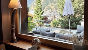 A cozy seating area with a view of a mountain and a town. - Alpenlodge (Zermatt)