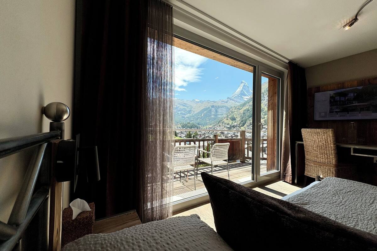 Une chambre d’hôtel dotée d’une grande fenêtre donnant sur les montagnes.