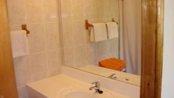 A bathroom with a white sink, mirror, and tiled walls.