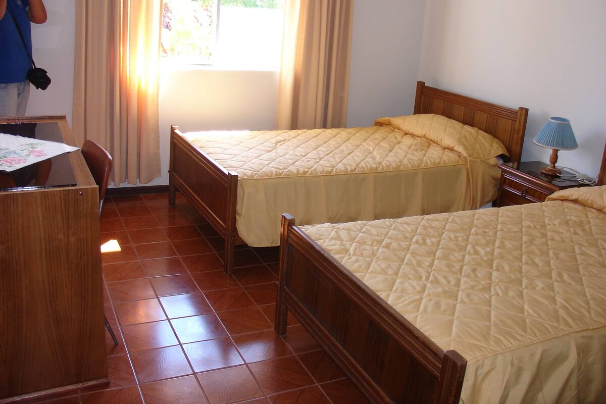 A hotel room with two beds, a desk, and a chair.