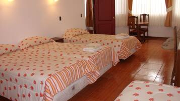 A hotel room with two beds, a wooden floor, a desk, and a chair.
